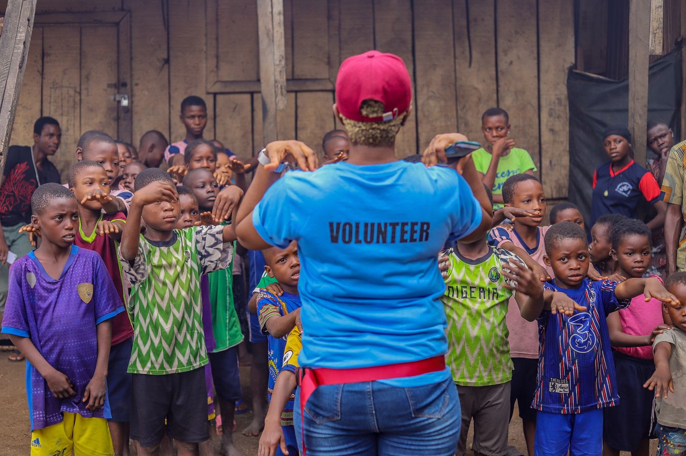 A volunteer leading children in an outdoor group activity.