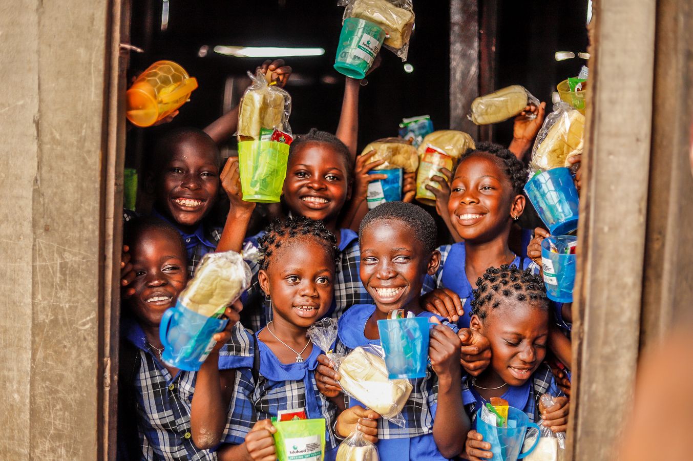 Children smiling while holding basic supply packs.